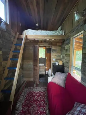 a small room with a bed and a staircase at Gracies Grotto Cabin in Powell River