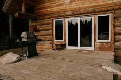 a front porch of a log cabin with a grill at Rustic Dream Cabin at Beaverfoot in Parson
