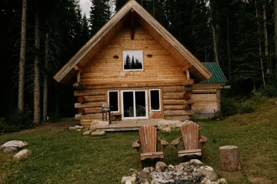 a log cabin with two chairs in front of it at Rustic Dream Cabin at Beaverfoot in Parson