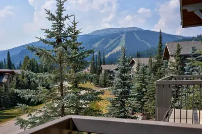 a view from the balcony of a house with trees and mountains at Trappers Landing #30 townhouse in Sun Peaks
