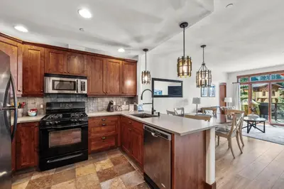 a kitchen with wooden cabinets and a stove top oven at Trappers Landing #30 townhouse in Sun Peaks