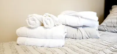 a stack of towels sitting on top of a bed at Cozy Comfort rooms in Nanaimo in Nanaimo