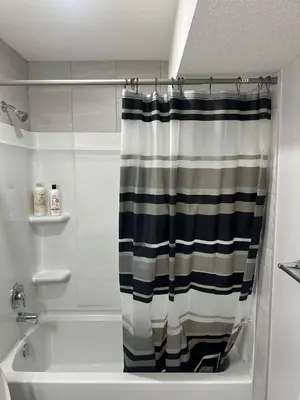 a bathroom with a black and white shower curtain at Luxurious Home in NW Calgary, Free Parking, High Speed Internet, Near Grocery and Airport in Calgary