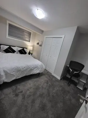 a bedroom with a bed and a black chair at Luxurious Home in NW Calgary, Free Parking, High Speed Internet, Near Grocery and Airport in Calgary