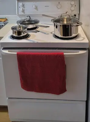 a white stove with two pots and a red towel on it at Cheerful 2BR suite, onsite free parking CARS or RV in North Vancouver