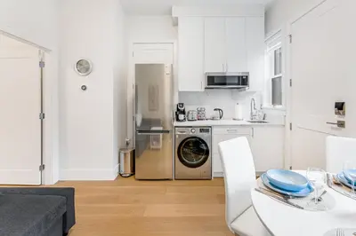 a kitchen with a refrigerator and a table with a dining room at New Bright Modern Guest Suite in Vancouver in Burnaby