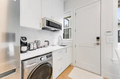 a white kitchen with a washing machine in it at New Bright Modern Guest Suite in Vancouver in Burnaby