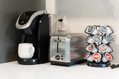 a coffee maker with stickers on it next to a cup at New Bright Modern Guest Suite in Vancouver in Burnaby
