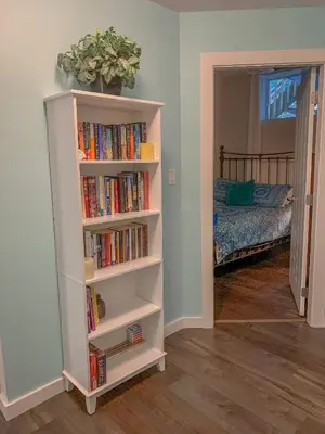 a book shelf filled with books next to a bedroom at Windslow Guest Suite at Kye Bay in Comox