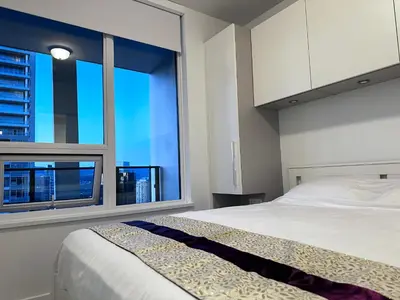 a bedroom with a bed and a large window at Relocation Special-New condo at Metrotown in Burnaby