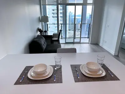 a white table with plates and glasses on top of it at Relocation Special-New condo at Metrotown in Burnaby