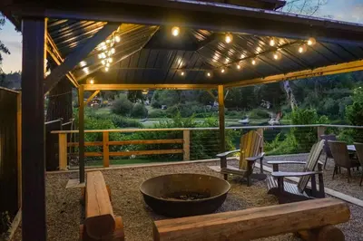 a patio with a fire pit and a bench and lights at Riverside by Cowichan Lake Cottages in Lake Cowichan