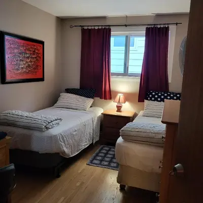 a bedroom with two beds and a window with red curtains at My Home in Calgary