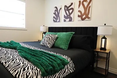 a bed with a green blanket and zebra pillows on it at Family Pet Friendly AC Disney Near WEM in Edmonton