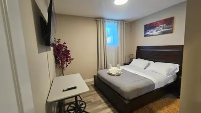 a bedroom with a bed and a tv and a table at Luxury Basement Suite with 2 Bedrooms, 2 Queen Beds, Free Wi-Fi, and Free Parking in Calgary
