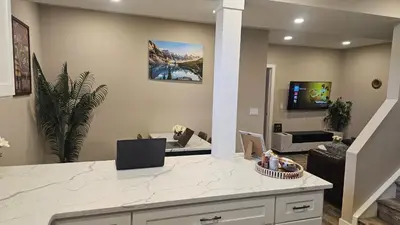 a kitchen and living room with a white counter top at Luxury Basement Suite with 2 Bedrooms, 2 Queen Beds, Free Wi-Fi, and Free Parking in Calgary