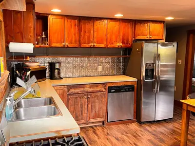 a kitchen with wooden cabinets and a stainless steel refrigerator at Bear Cove Cottages in Port Hardy