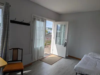 a bedroom with a door leading to a balcony at Gordie's Inn & Suites in Alert Bay