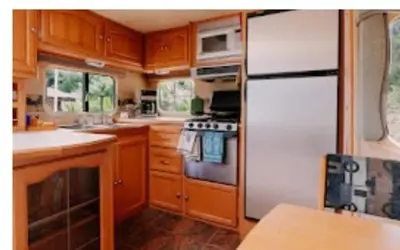 a kitchen with wooden cabinets and a white refrigerator at Lower Meadow on Saltspring Island in Fernwood