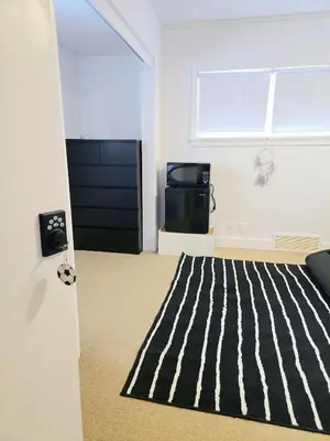 a bedroom with a black door and a striped carpet at Comfy Stylish Room in the Heart of Vancouver- Private Parking, Self Check-in & just 4 mins to Metrotown! in Vancouver