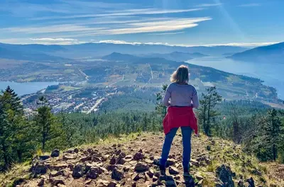 a woman standing on top of a hill overlooking a valley at Kelowfornia Lakeview Retreat in Kelowna