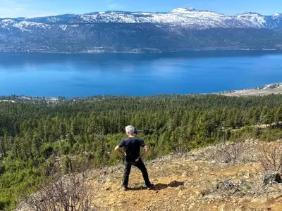 a man standing on top of a hill overlooking a lake at Kelowfornia Lakeview Retreat in Kelowna