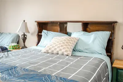 a bed with blue sheets and blue pillows at Airport 4BR2BA Mainfloor Suite 1min walk to bus stop in Calgary
