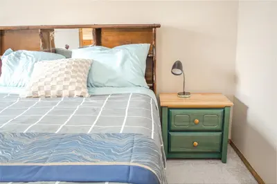 a bedroom with a bed and a nightstand with a lamp at Airport 4BR2BA Mainfloor Suite 1min walk to bus stop in Calgary