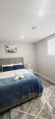 a bedroom with a bed with a blue blanket at fabulous and cozy guest suite in Calgary