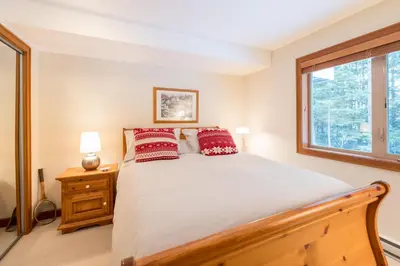 a bedroom with a bed with red pillows and a window at #24 Treeline in Whistler