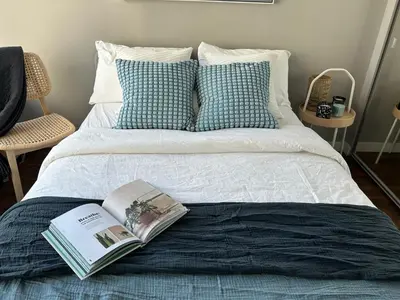 a bed with a book on top of it at Modern spacious Apt plus Solarium and Den in Downtown Vancouver with Parking and Pool in Vancouver