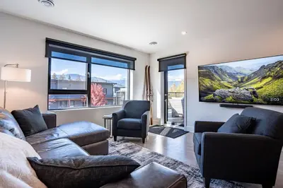 a living room with a couch and a tv on the wall at Base Camp Revy! in Revelstoke