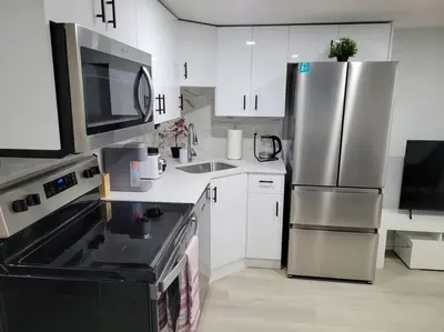 a kitchen with white cabinets and a stainless steel refrigerator at Beautiful Comfy Guest Suite in West EDM in Edmonton