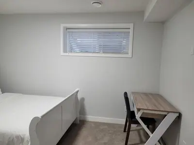 a bedroom with a bed and a desk and a window at Beautiful Comfy Guest Suite in West EDM in Edmonton