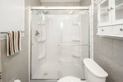 a white bathroom with a shower and a toilet at Nice 3 Bedroom 2 Bathroom Home Fenced yard near Downtown and YYC in Calgary