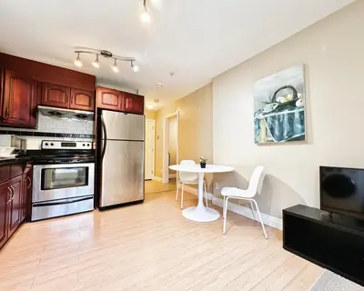 a kitchen with a table and a stainless steel refrigerator at Cozy 1bedroom Suite in Vancouver Westside in Vancouver