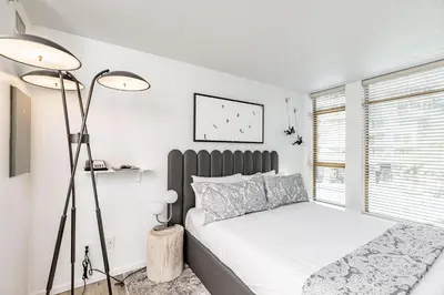 a white bedroom with a bed and a window at Cascade Lodge Premium Suite, with Pool & Hot Tub in Whistler