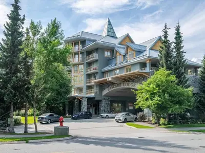 a large building with cars parked in a parking lot at Cascade Lodge Premium Suite, with Pool & Hot Tub in Whistler
