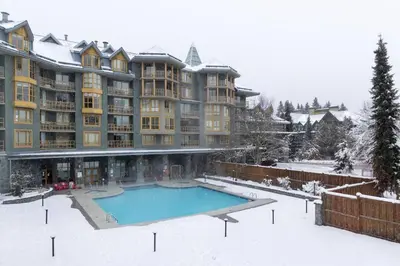 a large apartment building with a swimming pool in the snow at Cascade Lodge Premium Suite, with Pool & Hot Tub in Whistler