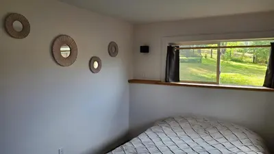 a bedroom with a bed and a window and mirrors at Haven Touchstone in Roberts Creek