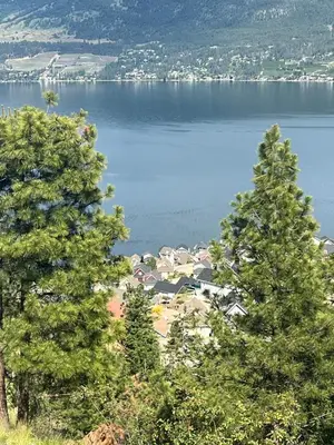 a view of a lake from between two trees at La Casa Lakeside Resort - Amazing Panoramic View Lakeside House with Pools, Hot Tubs & More! in Kelowna