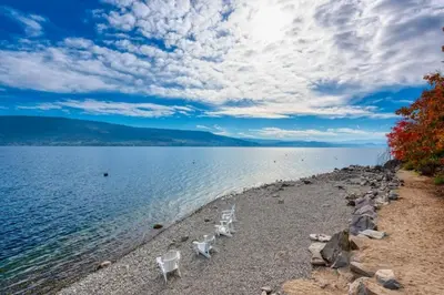 a group of chairs sitting on the shore of a lake at La Casa Lakeside Resort - Amazing Panoramic View Lakeside House with Pools, Hot Tubs & More! in Kelowna