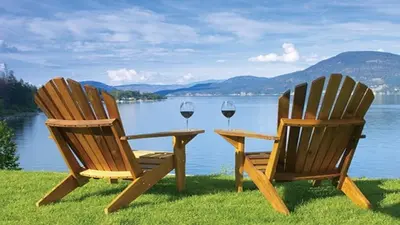 two chairs with wine glasses sitting next to a lake at La Casa Lakeside Resort - Amazing Panoramic View Lakeside House with Pools, Hot Tubs & More! in Kelowna
