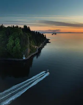 a boat in a body of water at sunset at The Altitude with Mountain & City Views, Pool & Hot Tub in Vancouver