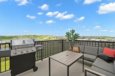 a patio with a grill and a table on a balcony at LUXURY LAKEVIEW HOME - 2500sqft of private space with 5 Beds, 4 Bath, 2 Living Rooms, Kitchen, AC, Jacuzzi, 10 Guests Max, Basement Not Included, 18-min to Airport, 20-min to Downtown, 80-min to Banff in Calgary