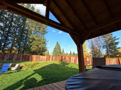 a backyard with a fence and a table on a patio at Eleanor Lodge - Entire House in Blue River in Blue River