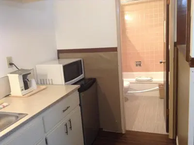 a small kitchen with a microwave and a bathroom at Falcon Nest Motel in Duncan