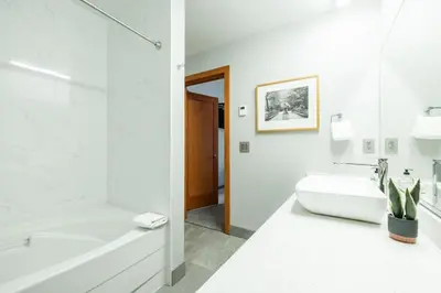 a white bathroom with a tub and a sink at Symphony by Outpost Whistler in Whistler