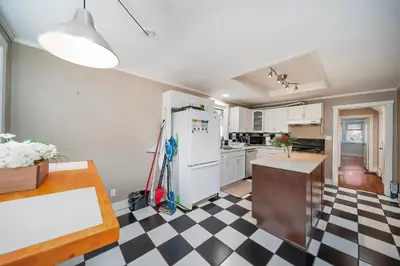a kitchen with a white refrigerator and a checkered floor at Charming Home Near UBC with Parking & Backyard in Vancouver