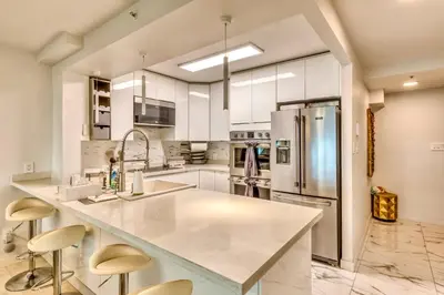 a kitchen with white cabinets and a stainless steel refrigerator at Art Deco Broadway Queen Room in Vancouver